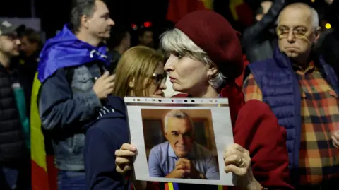 EPA A supporter woman holds a portrait of Calin Georgescu