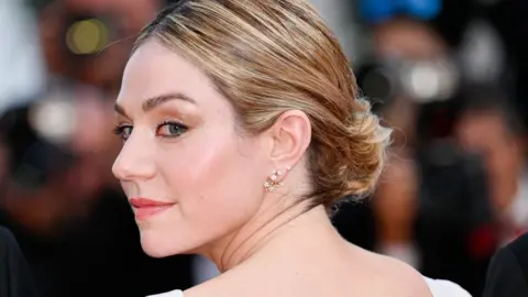 Getty Images Émilie Dequenne looking over her shoulder in front of a bank of photographers at the Cannes Film Festival in 2023