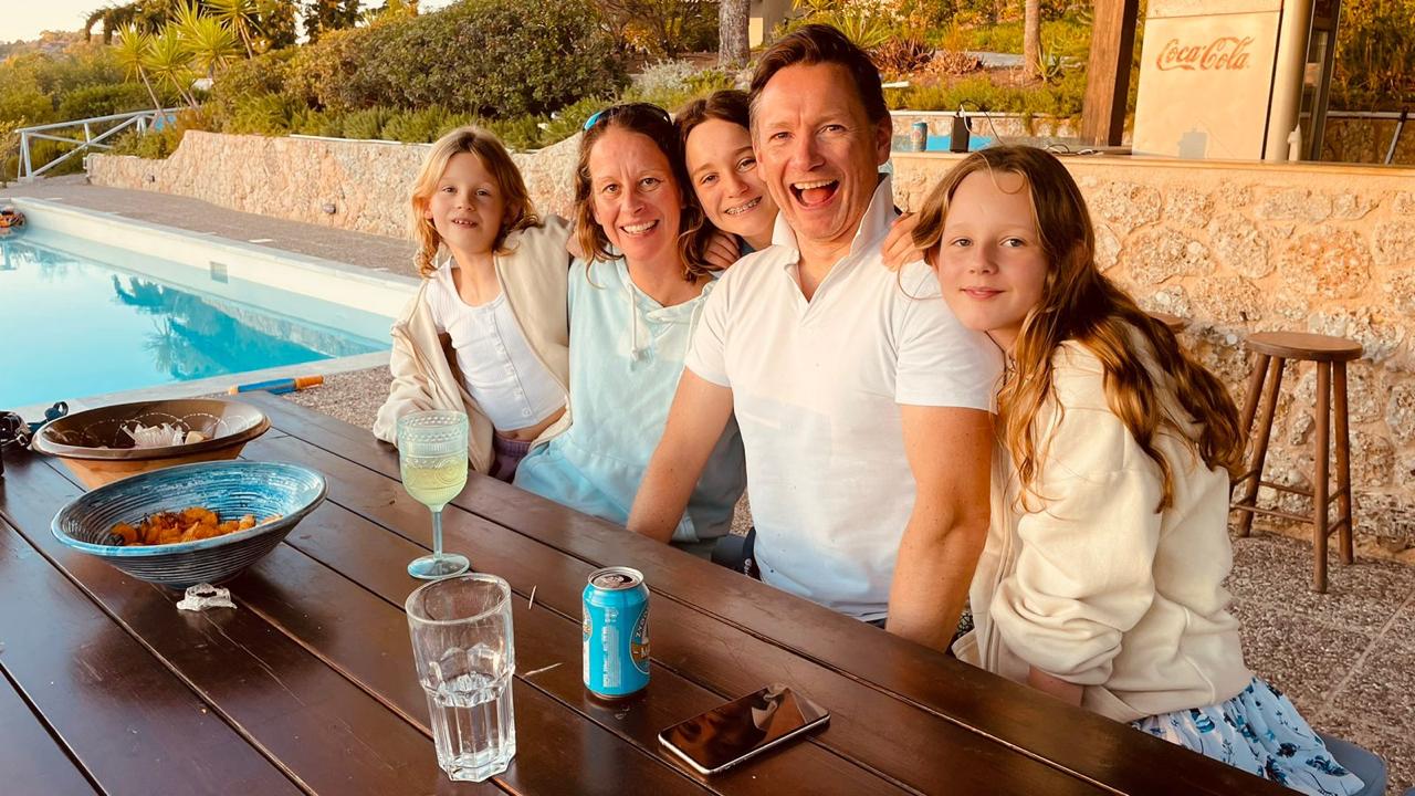 Family by a pool, smiling at the camera.