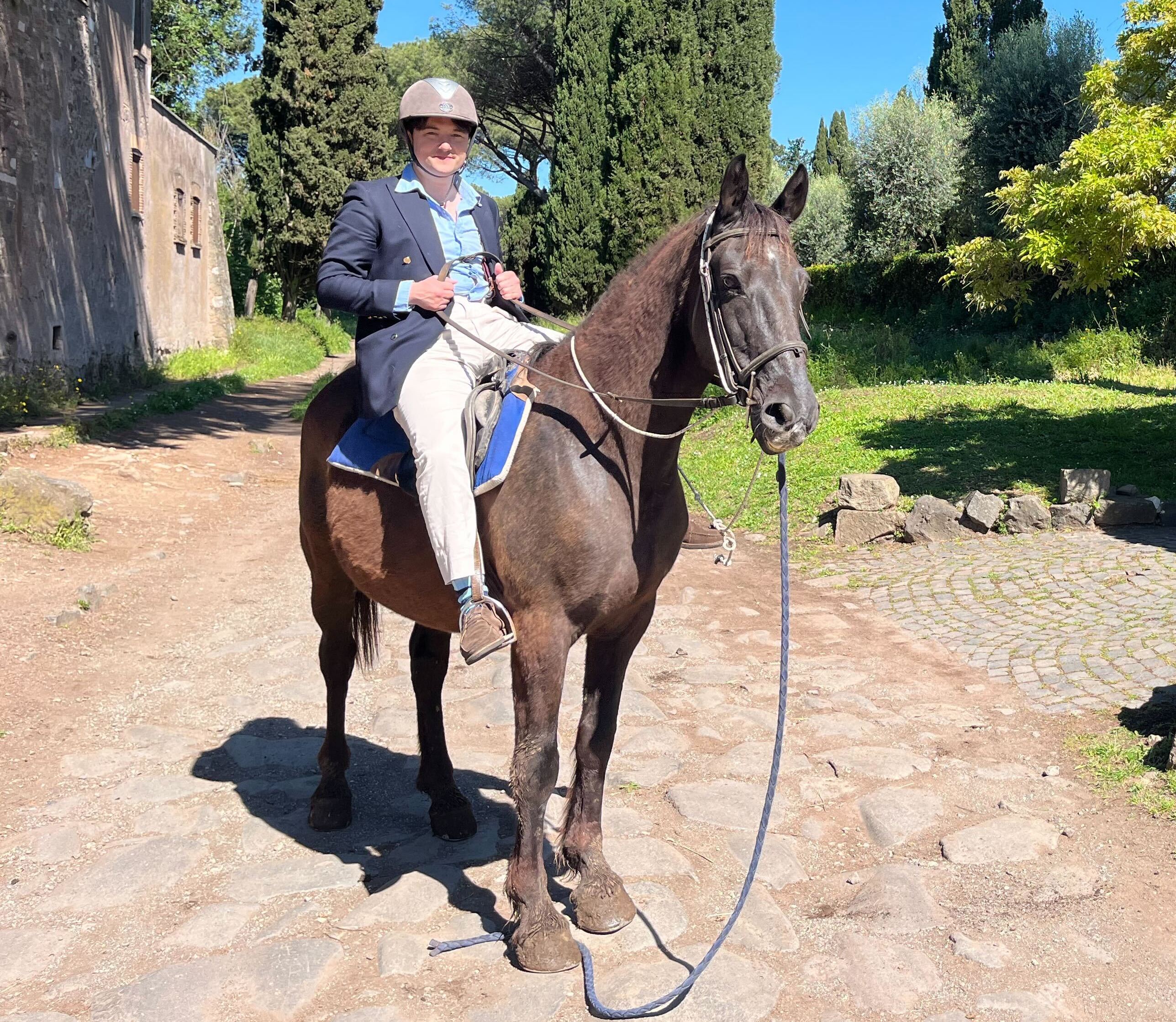 Person horseback riding on a stone path.