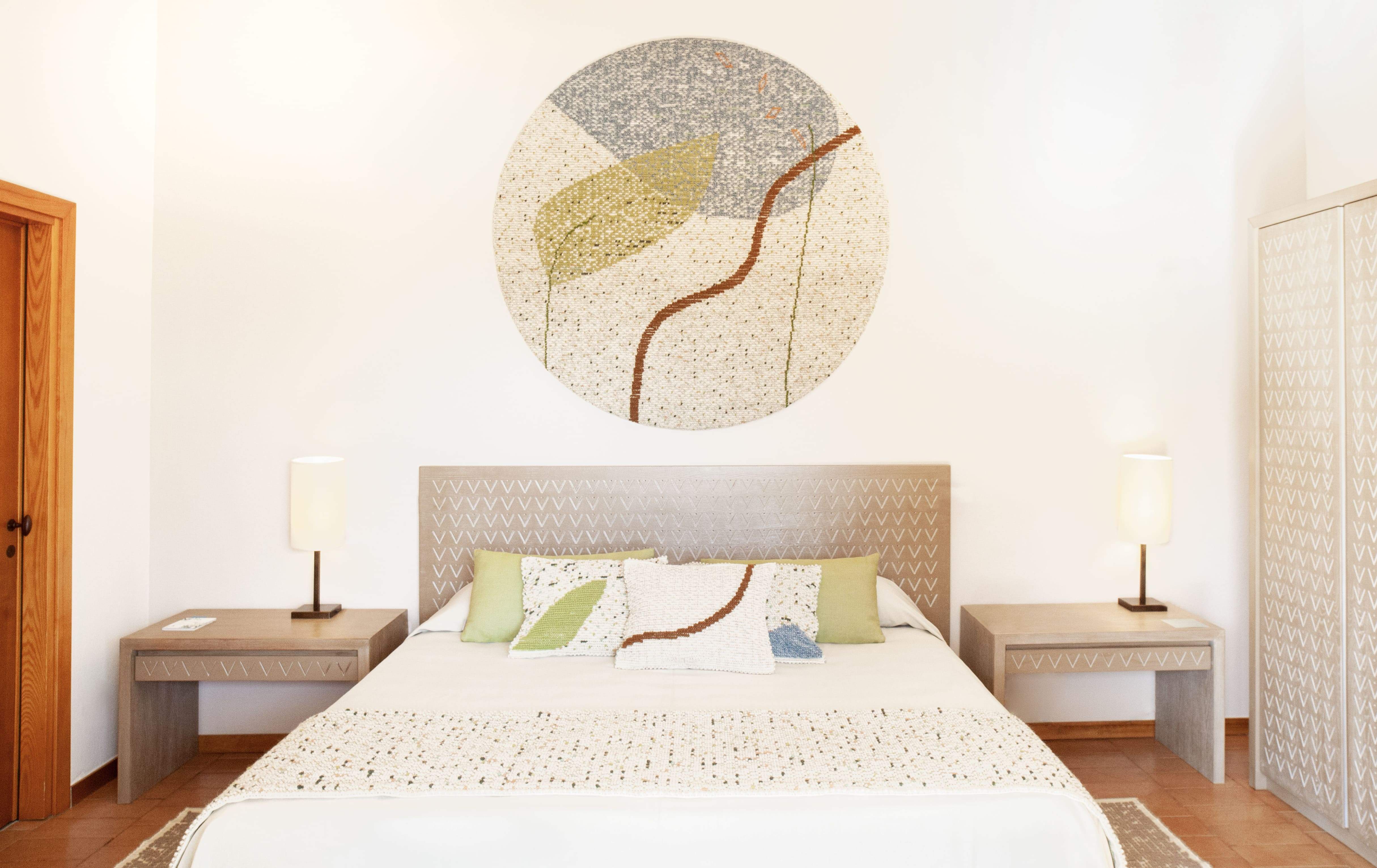 Hotel Aquadulci bedroom with bed and circular wall hanging.