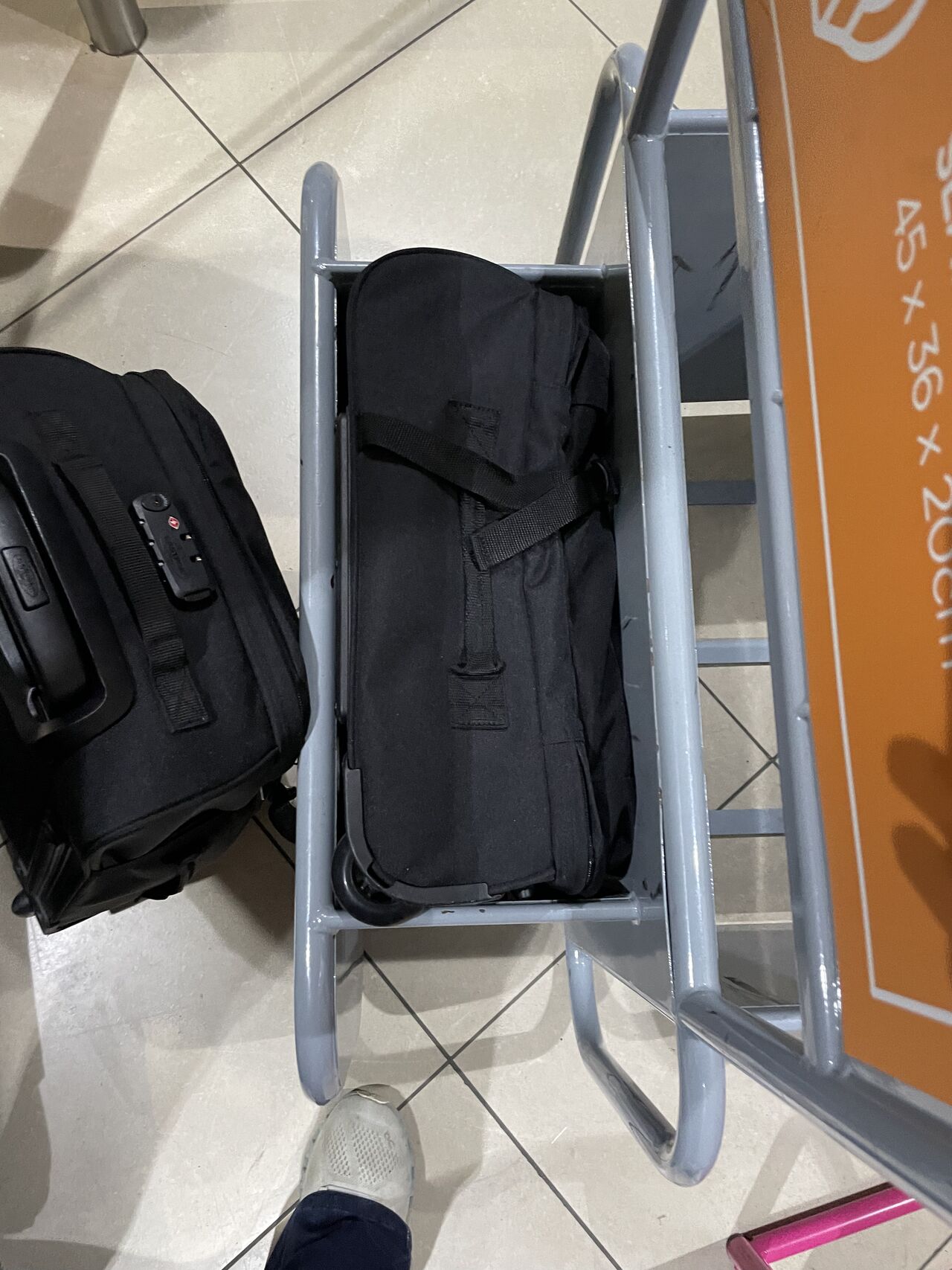 Black carry-on bags at an airport gate.