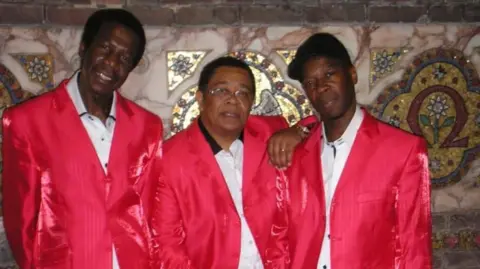 The Blackstones Leon Leiffer and two other members of The Blackstones wearing white shirts and bright red jackets