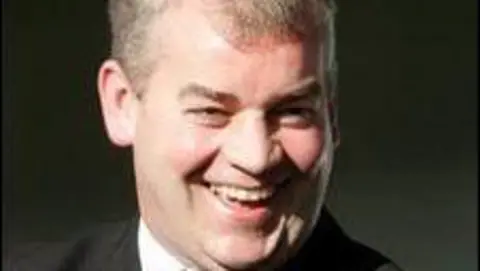 BBC Stephen Vaughan, who has short grey hair, smiles at the camera
