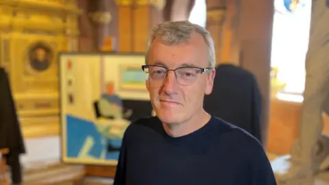 BBC The picture shows David MacMillan wearing glasses and a black jumper looking at the camera.