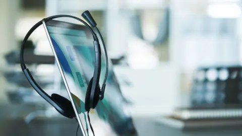 Getty Images A generic image of a phone headset on a computer monitor.