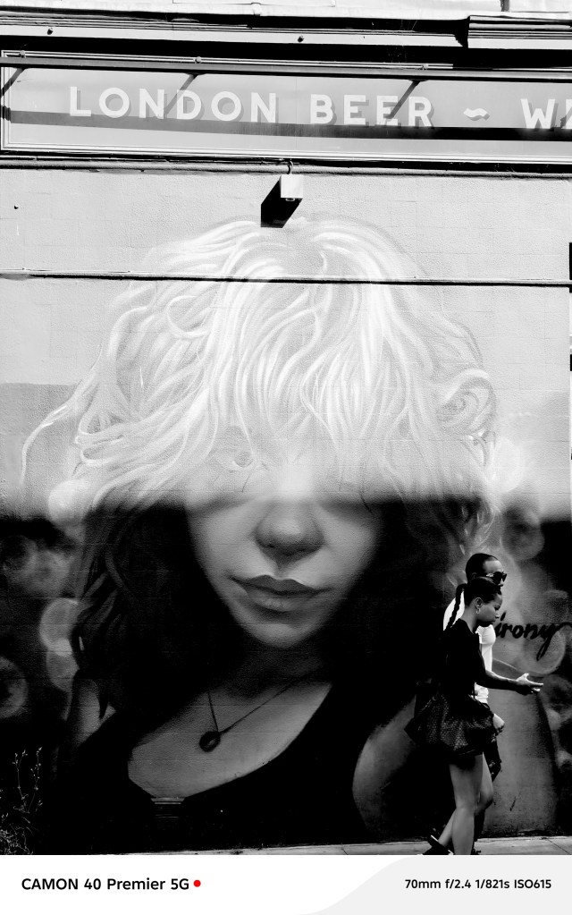 two people walking past a graffiti wall