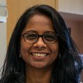 Swetha Murthy, Ph.D. (OHSU) Swetha Murthy, Ph.D., has long black wavy hair and a black and white pattern shirt, eye glasses, arms folded, and smiling in her lab