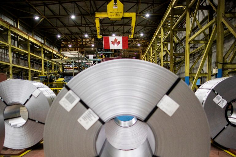 Steel coils and a flag of Canada are seen in the factory before Canada's Prime Minister-designate Mark Carney visits the ArcelorMittal Dofasco steel mill in Hamilton, Ontario, Canada