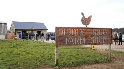 PA Media An outside image of the Diddly Squat Farm Shop sign, with people queueing to enter the shop