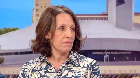 BBC A woman sitting in the BBC Breakfast studio wearing a blue and white dress