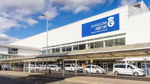 Getty Images several white taxis parked outside the front entrance to Glasgow Airport