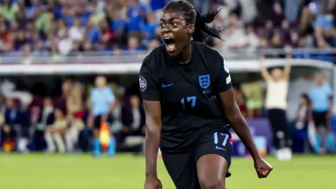 EPA/Shutterstock Michelle Agyemang in a dark England top, shouting and running on a football pitch.