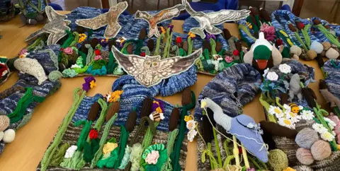 The Secret Society of Hertford Crafters A river scene, made out of fabric, on the floor, showing owls, birds, ducks, reeds, bees, and foliage.