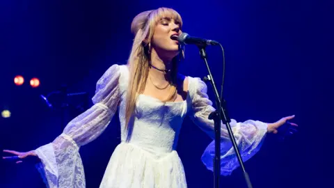 Getty Images Rianne Downey onstage, singing into a microphone - she has long blonde hair