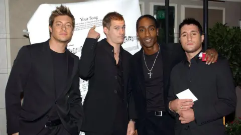 PA Media Four members of the Blue boyband all wearing black suits.