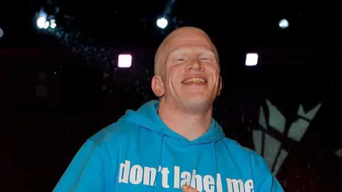 Getty Images Darnell Swallow smiles as he as he is evicted from the Big Brother house. He wears a light blue hoodie. 
