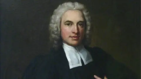 The New Room A painted portrait of Charles Wesley. He has grey curly hair and is wearing a black robe with a white cravat around his neck.