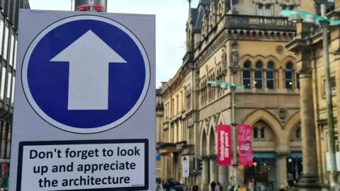 @ASignOfHumour A photo of a building in the centre of Glasgow with a sign that says Don't forget to look up and appreciate the architecture