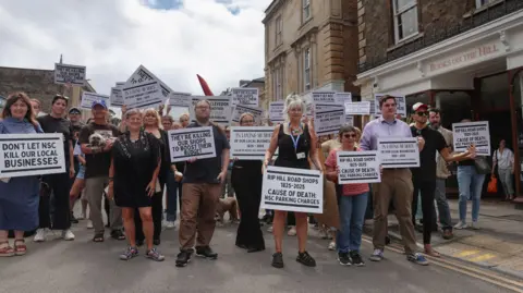 Jonathan Habens A few dozen protesters are holding placards which say parking charges will be the death of the high street