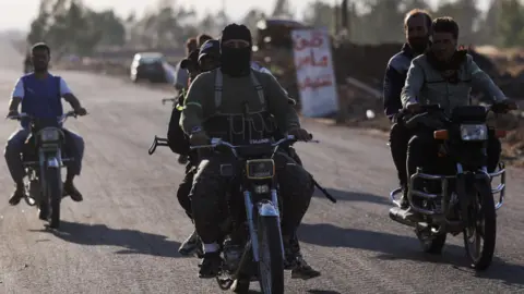 Reuters Armed Bedouin fighters ride motorbikes in southern Syria (17 July 2025)