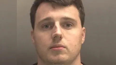 Merseyside Police A mugshot of Thomas Hooton. He has short dark hair and is wearing a dark top.