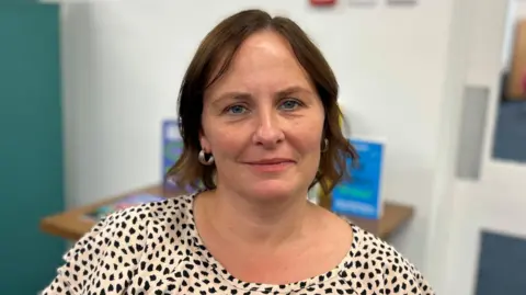 Beth Parsons/BBC Corrine Hunter, who has short brown hair and blue eyes. She is smiling in the photo.
