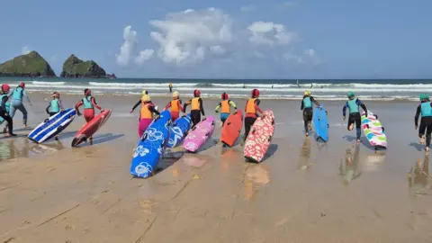 Carlyon Bay Surf Life Saving Club Young people with their surfboards heading into the sea