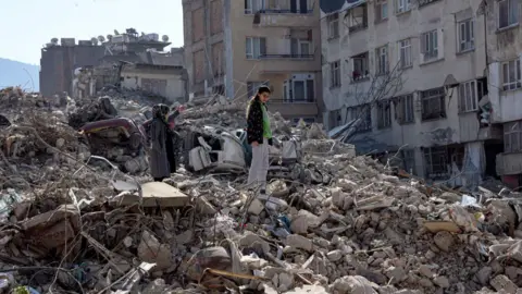 Getty Images A girl stands amongst the rubble of collapsed buildings in Turkey