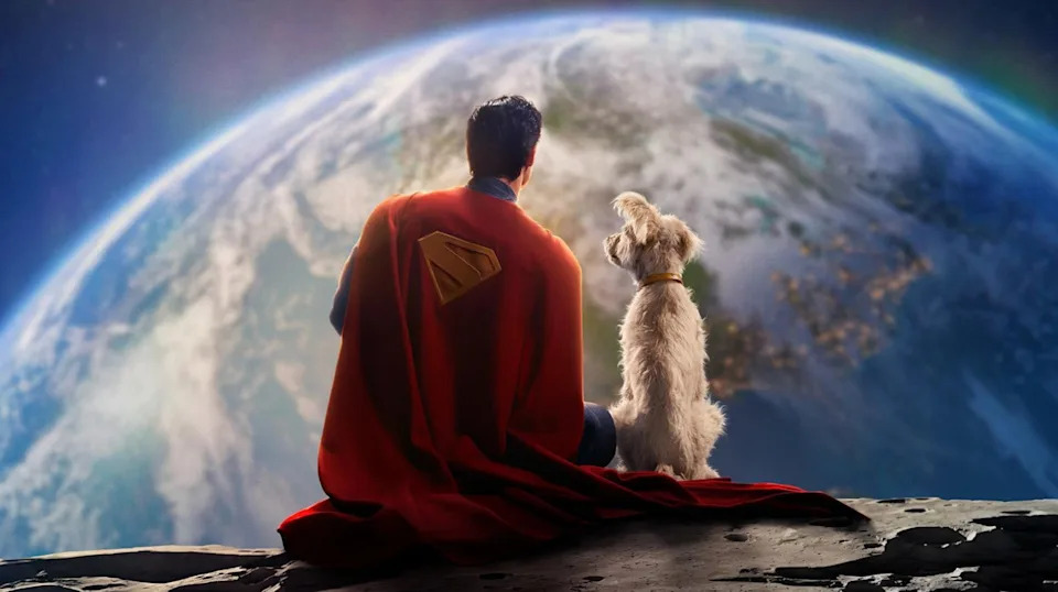 A man with black hair wearing a blue superhero costume and a red cape with a yellow 'S' symbol on it sits with his back to the camera, with a medium-sized white dog sitting next to him on the right. They're sitting on the Moon staring at Earth.