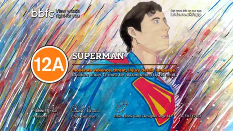 BBFC Superman, drawn in his iconic blue, red, and yellow costumer. He is emerging from a background of multicoloured streaks. The word 'Superman' and an orange circle around the digits '12A' overlays the design.