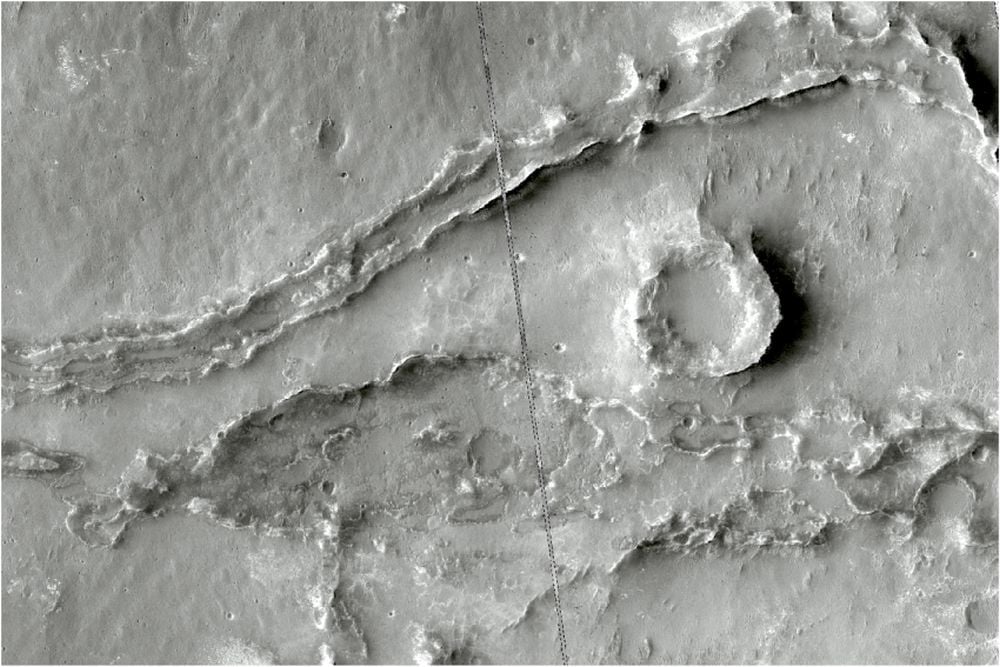 This HiRISE image shows two branches of an FSR. The river split into two then rejoined outside of the image. The lower branch is heavily eroded and quite spread out, the upper branch is narrower but more clearly preserved. They could've had different exposure times or undergone different geological processes. Or they could be from different periods of water activity. There are remnants of an infilling material within the ridge and a meander where the branch turns back towards the lower trunk. The mesa in between the branches could be a crater that was filled with the same sediment as the FSR. Image Credit: HiRISE Image: ESP_085519_1585 NASA/JPL/University of Arizona. Licence type: Attribution (CC BY 4.0)