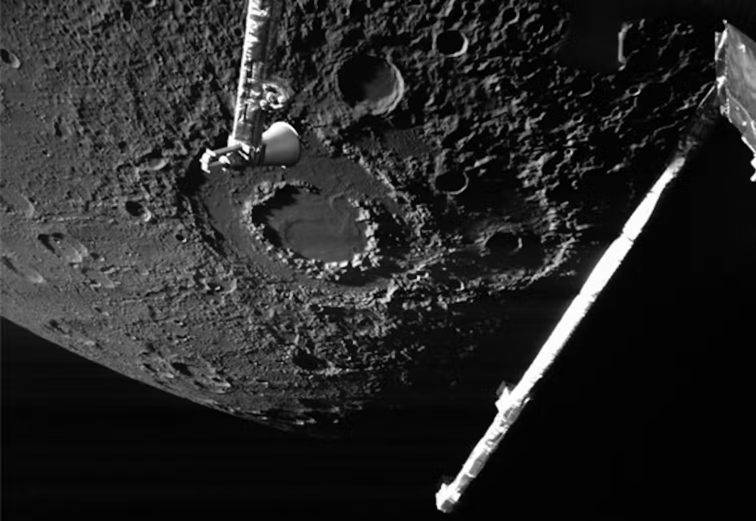 a black and white photo of a spacecraft over the cratered surface of Mercury