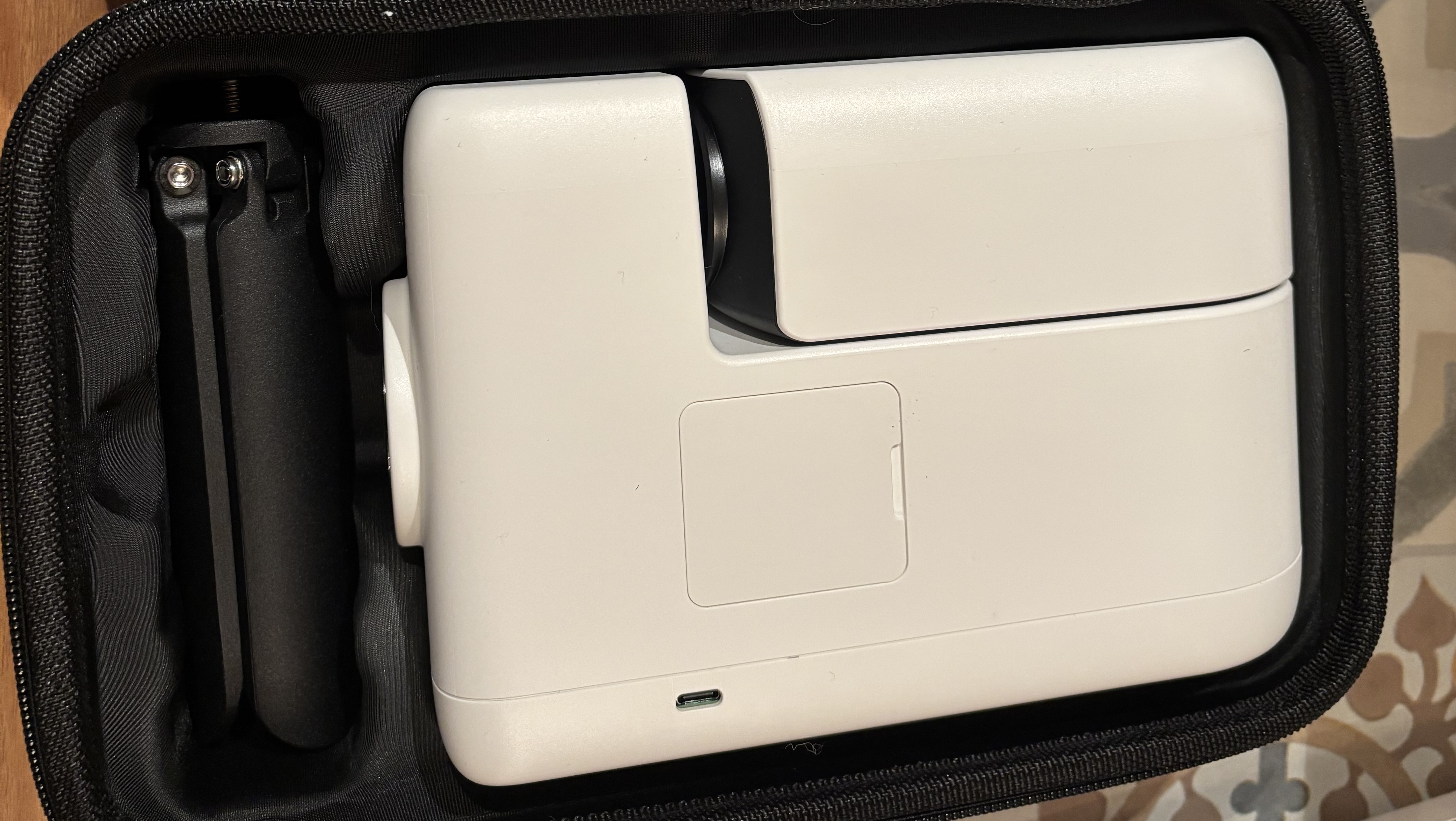 A white smart telescope is folded up and its tripod is too, all placed inside a carry bag.