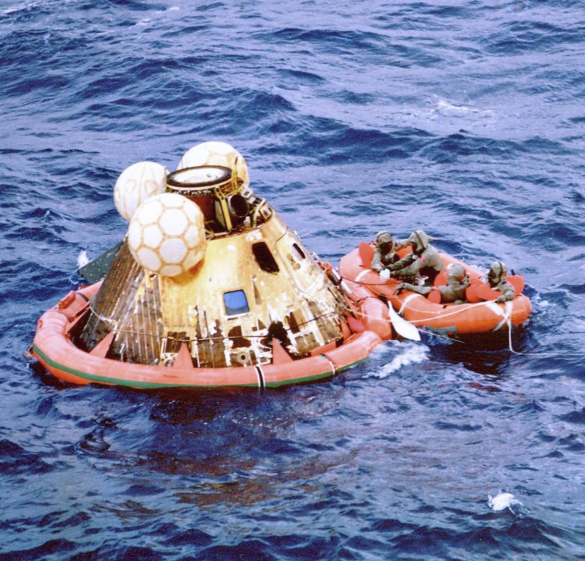 The crew of Apollo 11 floats on the ocean after their return from the Moon as Navy divers assist in retrieving them (Credit : NASA)