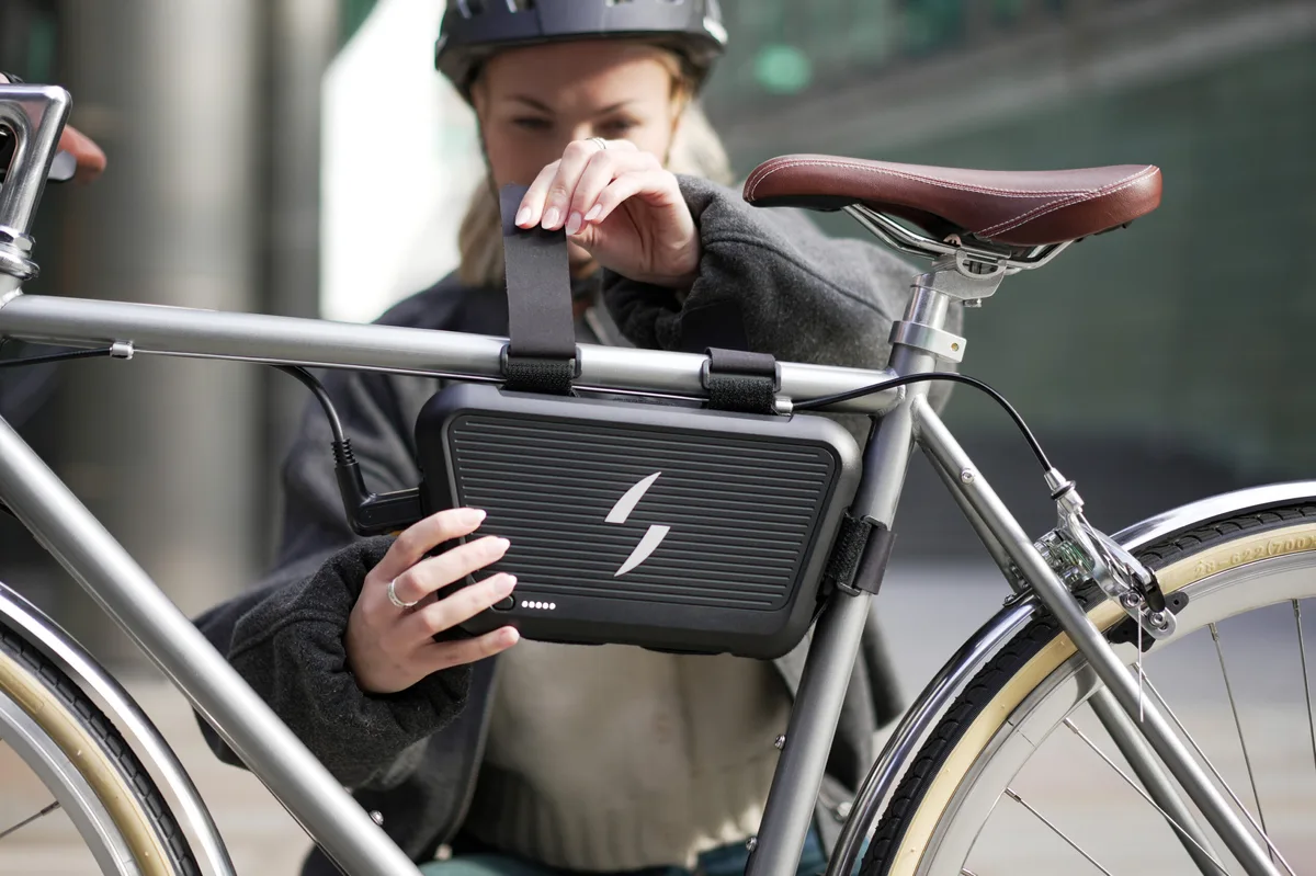Cyclist strapping the Swytch Go battery pack to a top tube