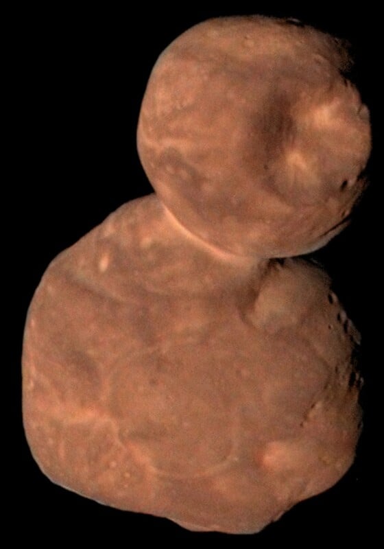 Two reddish, irregularly shaped, rocky objects are fused together, resembling a snowman, against a black background. This is a close-up view of the Kuiper Belt object Arrokoth (Ultima Thule).