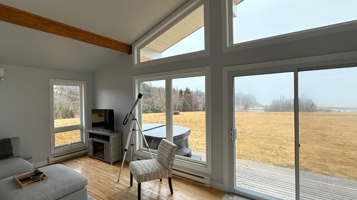 A telescope next to glass windows at a cabin overlooking the Canadian wilderness
