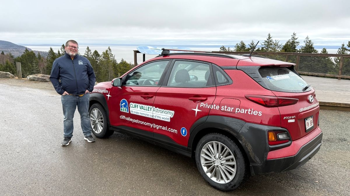 A man stands next to a red compact car in Canada