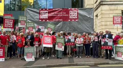 BBC A group of protestors, many with Stop Lime Down placards, in front of Wiltshire Council HQ.