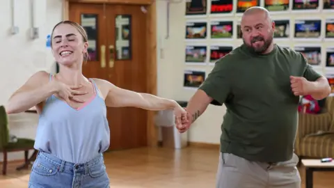 Liverpool's Royal Court Emma Grace Arends and John May dance in rehearsals, holding hands with their arms outstretched 