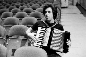 Billy Joel sits in the auditorium seating during a soundcheck, playing accordion, New York, 7th December 1977. (Photo by Michael Putland/Getty Images)
