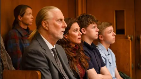 BBC/LA Productions/Kerry Spicer This candid still from the drama shows several of the character sitting in a court room. They are all staring directly ahead.