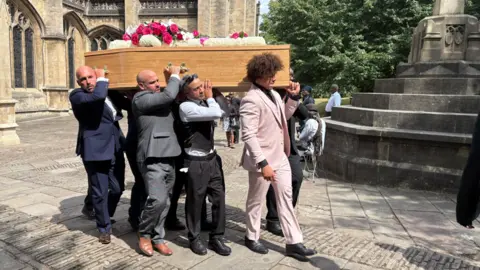 BBC A group of men wearing suits containing the coffin which David 'Syd' Lawrence is in outside St Mary Redcliffe Church