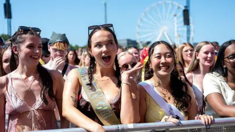 Getty Images Fans in the front row at a music festival smile in the sunshine