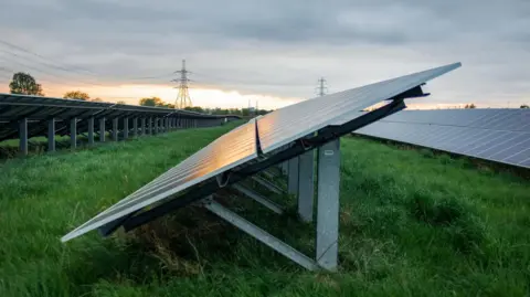 Getty Images A number of slanted solar panels built in a field