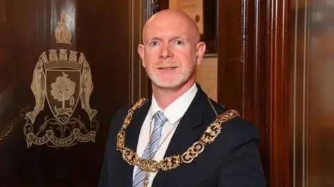 Glasgow City Council Philip Braat - a bald man wearing a suit and the Lord Provost's chain of office - looks into the office while in an office