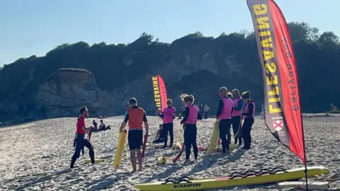 Carlyon Bay Surf Life Saving Club A group of people in wetsuits with rescue tubes on a beach