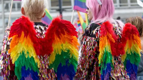 BBC Pride parade goers with angel wings in the style of the rainbow flag.
