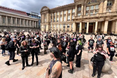BBC Black Sabbath fans, many dressed in black, congregate in Birmingham's Victoria Square